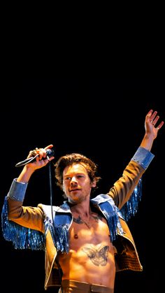 a shirtless man holding a microphone on stage