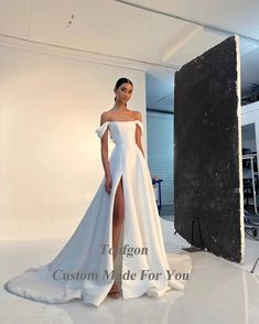 a woman in a white wedding dress posing for the camera with her leg slit down