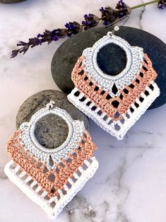 two crocheted earrings sitting next to each other on top of a stone slab