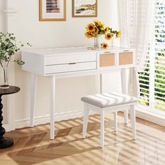 a white desk and chair with sunflowers in vase on the table next to it