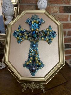 a cross made out of glass beads on top of a wooden table next to a mirror