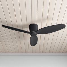 a black ceiling fan mounted to the side of a wall in a room with wood paneling