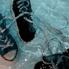 two pairs of black shoes in water with white laces on the top and bottom