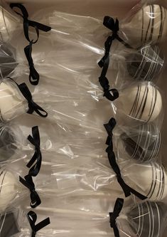 an open box filled with white chocolate covered donuts and black ribbon tied around them