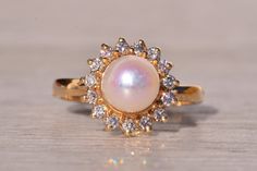 a close up of a ring with a pearl and diamonds on the bottom, sitting on a table