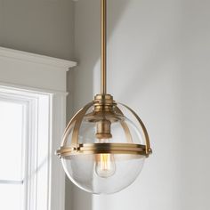 a light fixture hanging from the ceiling in a room with white walls and window sill