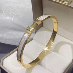 These Are Highly Polished Fashion Titanium Stainless Steel Gold Plated Pieces That Will Last A Lifetime. It Is Corrosion And Scratch Resistant And Hypoallergenic. The Bangle Is An Oval Shape That Sits Perfectly On The Wrist With The H Or Always On Top. The H/Front Are Set In A White Mother Of Pearl Style Tone. Outside Circumference Of Bracelet Is Approximately 19cm Brand New Gold Tone Color White Stainless Steel Bangle Bracelets, White Stainless Steel Bangle Bracelet, Luxury White Stainless Steel Bracelets, Luxury White Stainless Steel Bracelet, White Stainless Steel Formal Bracelets, Formal White Stainless Steel Bracelets, White Metal Oyster Bracelet, White Stainless Steel Bracelet, White Oyster Bracelet Bangle