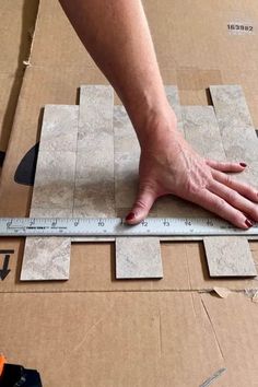 someone is measuring out the tile on top of a cardboard box