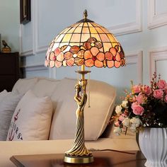 a table lamp sitting on top of a wooden table next to a vase filled with flowers