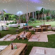 an outdoor area with tables, benches and umbrellas on the grass in front of trees