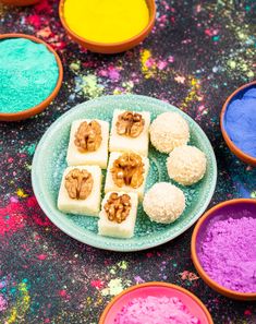 colorful powdered food on a blue plate with bowls of nuts and other foods in the background