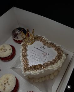 a heart shaped cake in a box surrounded by cupcakes