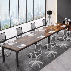 an empty conference table with chairs around it in front of a large window overlooking the city