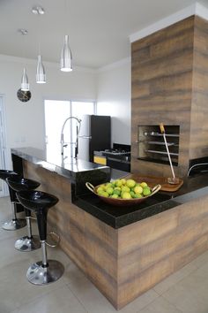 a bowl of fruit sitting on top of a kitchen counter next to two bar stools