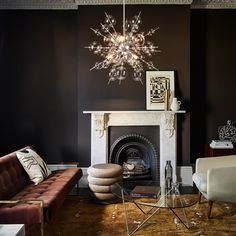 a living room filled with furniture and a chandelier hanging from the ceiling over a fire place