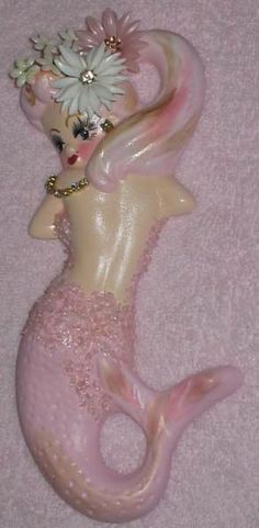 a pink mermaid figurine with flowers in her hair