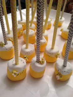 there are many yellow and white candles on the table with straws sticking out of them