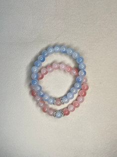 two bracelets with pink and blue beads on white background, one has a silver beaded charm