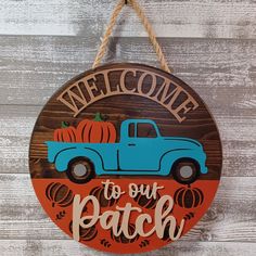 a sign that says welcome to our patch with an old blue truck and pumpkins