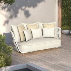 a white couch sitting on top of a wooden floor next to a plant filled wall