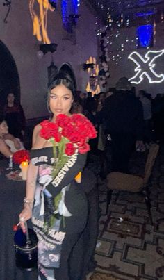 a woman is holding flowers in her hand and posing for the camera at a party