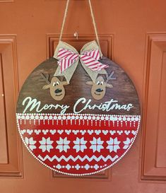 a wooden sign hanging on the front door of a house with reindeer heads and bows