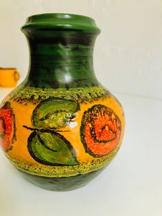 a green and yellow vase sitting on top of a table