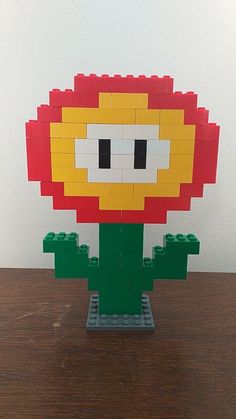 a lego model of a flower on top of a wooden table next to a white wall