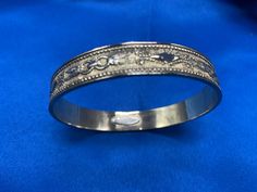 This is a vintage bangle in a gold finish from the famous Whiting & Davis Co. that started back in the late 1800's. This bangle as with most of their jewelry is made of gold-plated metal. It is truly costume jewelry but on the higher end. This type of jewelry started being made in the '50's and on.  The bangle has a a ring and feather design and it is a raised on the outside and smooth and shiny on the inside. There is a Whiting Davis in small raised metal on the inside of the bracelet as well. Victorian Hinged Cuff Bangle Bracelet, Victorian Hinged Cuff Bracelet, Heirloom Etched Bangle For Ceremonial Occasion, Formal Adjustable Brass Bangle, Ceremonial Heirloom Etched Bangle, Ornate Hinged Bangle Bracelets, Ceremonial Metal Bangle Bracelet, Ornate Hinged Bangle Bracelet, Gold Bangle With Decorative Band As Gift