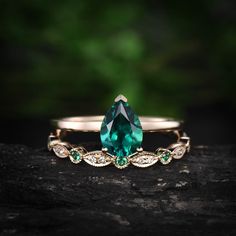 an emerald colored ring sits on top of a rock