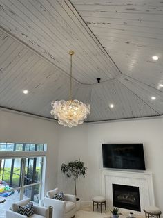 a living room filled with furniture and a chandelier hanging from the ceiling over a fire place