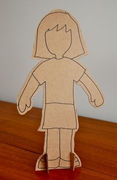 a paper doll is standing on a wooden table