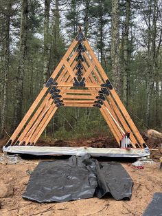 a wooden structure in the middle of a forest with tarp coverings around it