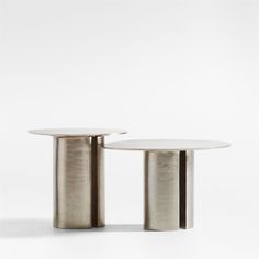 two round tables sitting side by side in front of a white wall