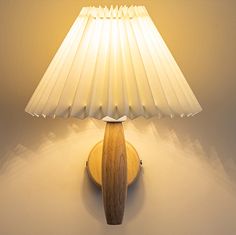 a wooden table lamp with a white shade on the top and bottom of it's base