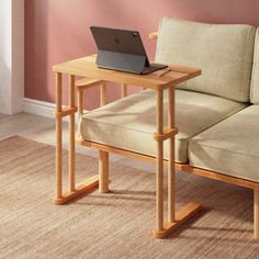 a laptop computer sitting on top of a wooden table next to a beige couch in a living room