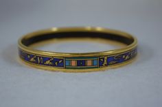 "C1980's, Michaela Frey gold plated Egyptian Revival bangle bracelet This is a 7-1/2\" bracelet, 3/8\" wide the bracelet is used and shows some wear along the edge (very small scuff or impressions in the gold) Repeating Egyptian designs on band" Collectible Yellow Gold Bangle Bracelet, Collectible Enamel Bangle Jewelry, Formal Enamel Bangle Bracelet, Yellow Gold Bangle Bracelet, Gold Enamel Bangle Bracelet, Gold Enamel Bangle Bracelets, Antique Gold Enamel Bracelets, Symbolic Gold Bracelets For Ceremonial Occasions, Symbolic Gold Bracelets For Ceremonies