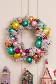 a christmas wreath is hanging on the wall next to other holiday decorations and ornaments in front of a doll house