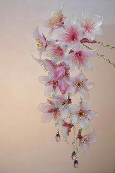 pink and white flowers hanging from the ceiling in front of a wall with water drops