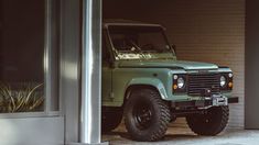 a green land rover parked in front of a building