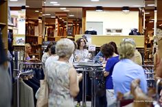 a group of people standing in front of a book store filled with books and magazines