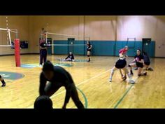 a group of people playing volleyball in a gym