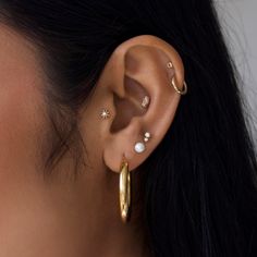 Introducing our stunning collection of 9k Solid Gold ear party pieces Dainty, Sparkly & Stackable styles designed to mix & match, creating a look that’s personal to you! These timeless treasures are made to last a lifetime, making them perfect for everyday wear in specialist ear piercings. Fits: Lobe, Upper Lobe & Conch Wear Pearl when manifesting luck and wealth. Read more in our guide to beautiful gemstones here  Buying a gift for someone special? Why not add the finishing touch with one of our gorgeous gift cards and gift bags? Click here to view Ear Stack With Conch, Pearl Ear Piercings, Ear Party Piercings, Cute Ear Stacks, Classic Gold Piercings With Matching Earrings, Stackable Earring Ideas, Classic Single Small Hoop Earring, Classic Gold Plated Ear Cuff, Gold Small Hoop Classic Piercings