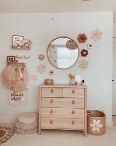 a dresser and mirror in a room with flowers on the wall above it, along with other decorations