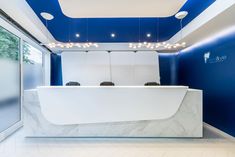 an office with blue walls and white marble counter tops, along with lights hanging from the ceiling