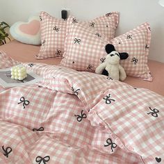 a teddy bear sitting on top of a bed with pink and white checkered sheets