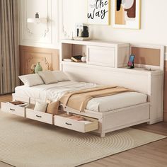 a white bed with drawers underneath it in a room next to a rug and window