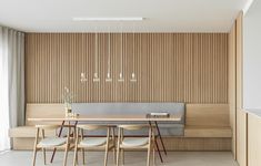 a dining room table with four chairs and a bench in front of the wall that has vertical slats on it