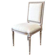 a white upholstered chair with silver trimmings on the back and sides