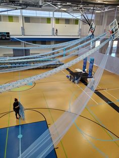 an indoor basketball court with nets on the floor and two people standing in front of it